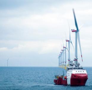 Wind farm with red boat in foreground